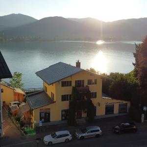 a building with cars parked in front of a lake at Lake & Mountain View Villa Tegernsee - including 4 Rooms for Family & Friends in Tegernsee