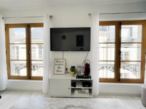 sala de estar con TV en la pared y ventanas en Magnifique logement au pied du Château en Blois