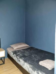 Ce lit se trouve dans un dortoir doté d'un mur bleu. dans l'établissement Manhattan Suites by NAJ, à Penampang