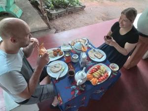 a man and a woman sitting at a table with food at sigiriya village hostel in Sigiriya