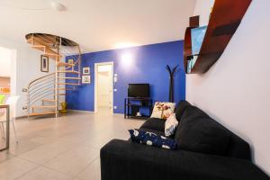 a living room with a black couch and a tv at Parcheggio Privato e Aria Condizionata "CASA DEI COLORI" in Lido di Camaiore