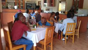 a group of people sitting at tables in a restaurant at Pits lodge in Polokwane