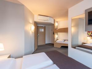 Habitación de hotel con cama y espejo en B&B Hotel Schweinfurt-City en Schweinfurt