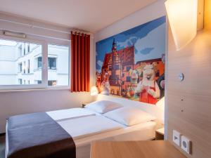 シュヴァインフルトにあるB&B Hotel Schweinfurt-Cityのベッドルーム1室(壁に絵画が描かれたベッド1台付)