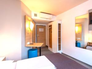 a hotel room with a bed and a desk in it at B&B Hotel Schweinfurt-City in Schweinfurt