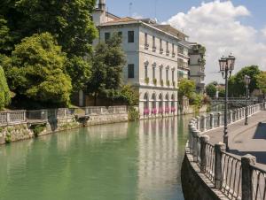 einen Fluss in einer Stadt mit einem Gebäude und einer Brücke in der Unterkunft Giovigemini Apartment in Treviso