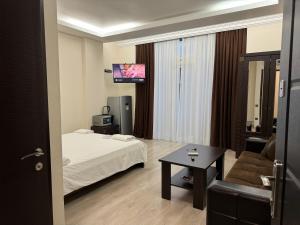 a hotel room with a bed and a couch and a tv at Iko's Family Apartments in Batumi