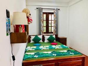 a bedroom with a bed with a teddy bear and a window at Ambuluwawa View Inn in Gampola