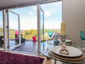 a dining room with a glass table and a view of a deck at Greenslades View in Dittisham