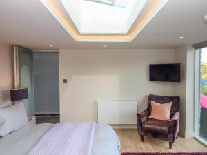 a bedroom with a bed and a chair and a skylight at Greenslades View in Dittisham