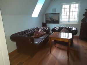 a living room with a leather couch and a table at Der Westflügel Admiralssuite WF-46 in Stolpe auf Usedom
