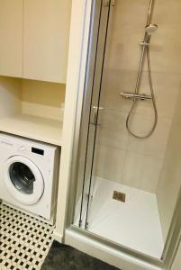 a shower in a bathroom with a washing machine at Villa la Rabolière quartier Lajarrige à La Baule in La Baule