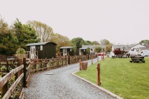 a gravel road with a fence and some buildings at The Wilson Arms in Torver