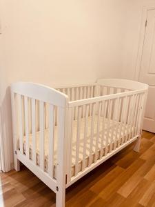 - un lit bébé blanc dans une chambre dotée de parquet dans l'établissement Spacious 3 bedrooms family living in Rosetta, à Rosetta
