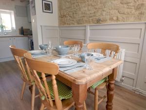 una mesa de madera con sillas, platos y vasos. en Pass the Keys The Pippins a Cotswold cottage and garden parking en Stow on the Wold