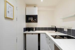 a white kitchen with a sink and a microwave at Cute Studio in the 16th near the Arc de Triomphe in Paris