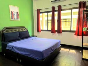 a bed in a room with green walls and windows at U&D guest house in Bangkok