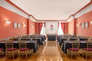a conference room with tables and chairs and a screen at Exe Doña Carlota in Ciudad Real