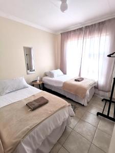 a hotel room with two beds and a window at MV self-catering - Rooms in Bloemfontein