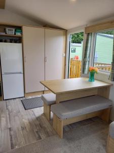uma cozinha com uma mesa, bancos e um frigorífico em Lindens on the Lido em Knaresborough