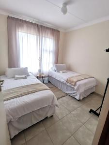 two beds in a room with a window at MV self-catering - Rooms in Bloemfontein