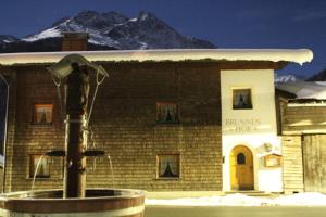 un edificio con una fuente frente a un edificio con una montaña en Brunnenhof Apartments, en Pettneu am Arlberg