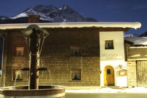a building with a fountain in front of a building with a mountain at Brunnenhof Apartments in Pettneu am Arlberg