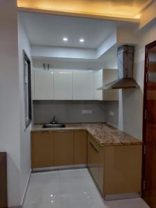 an empty kitchen with white cabinets and a sink at Minato Homz in Gurgaon