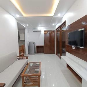 uma sala de estar com um sofá e uma televisão de ecrã plano em Minato Homz em Gurgaon