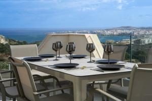 una mesa blanca con sillas y copas de vino. en Lux Sea&Country Views with Pool, en Mellieħa