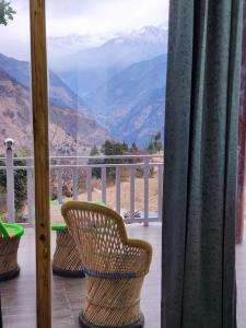 a balcony with chairs and a view of mountains at Raithal jungle resort in Bhatwāri