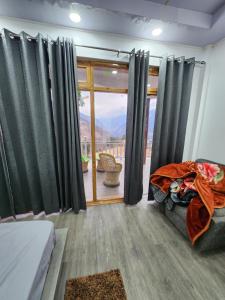 a bedroom with black curtains and a large window at Raithal jungle resort in Bhatwāri