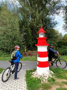 a woman on a bike next to a red and white lighthouse at Rafting & Via Ferrata Base Camp in Vadu Crişului