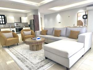 sala de estar con sofá, sillas y mesa en Luxurious 3 Bedroom Apartment - 5 minutes to Boulevard, en Riad