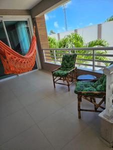 uma varanda com 2 cadeiras e uma rede de descanso em ARCO IRIS KITNETS em Fortaleza