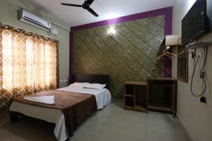 a bedroom with a bed and a tv and a window at Wayanad regal residency in Kalpetta