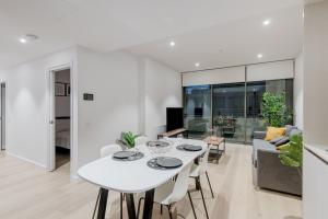 a white dining room with a white table and chairs at Modern 2 Bedroom Apartment Darling Square in Sydney