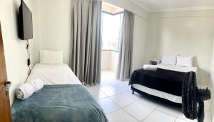 1 dormitorio con 2 camas y TV. en Apartamentos em Vicente Pires, en Brasilia