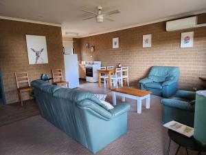 a living room with blue furniture and a kitchen at Pomonal Cottages Grampians in Halls Gap