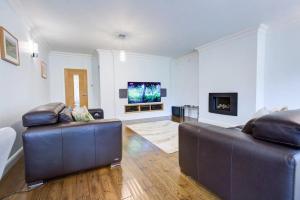 a living room with two leather couches and a flat screen tv at Pass the Keys Spacious House Near Chelmsford in Chelmsford