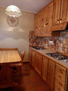 uma cozinha com armários de madeira e uma mesa em La tua piccola casa a Pecol em Mareson