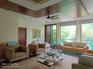 un soggiorno con divani e tavolo in vetro di Pristine home near New Friends colony a Nuova Delhi