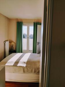a bedroom with a bed with green curtains and a window at Bel appartement refait à neuf, calme et ensoleillé in Cabourg