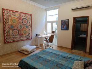 a bedroom with a bed and a desk and a rug on the wall at Pristine home near New Friends colony in New Delhi