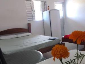 Habitación con cama, nevera y mesa. en Suíte Canto Caiçara, en Ubatuba