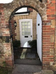 an archway leading to a white door in a brick building at Charming property in the heart of Midhurst in Midhurst
