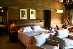 a bedroom with a bed and two chairs at Mirador da Montanha in Praia Grande