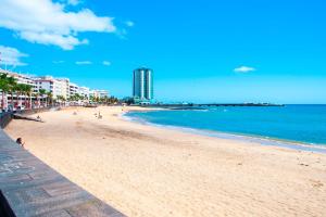 a beach with people and buildings and the ocean at Beachfront arrecife views in Arrecife