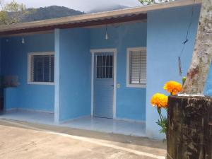 una casa azul con una puerta azul y flores amarillas en Suíte Canto Caiçara, en Ubatuba