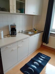 a kitchen with white cabinets and a sink and a rug at Stellas Monteurwohnungen in Werdau